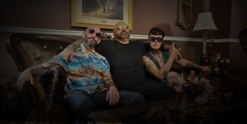 Three people sitting on a couch in a dimly lit room with decorative elements.