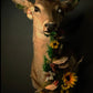 Taxidermy deer head with floral decorations on a dark background